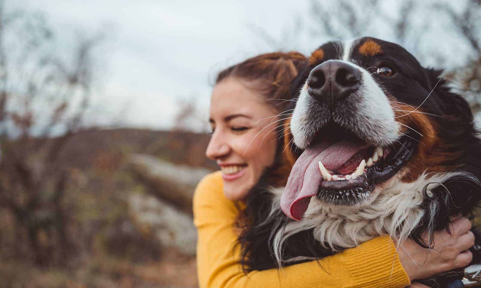 A woman hugging her smiling dog